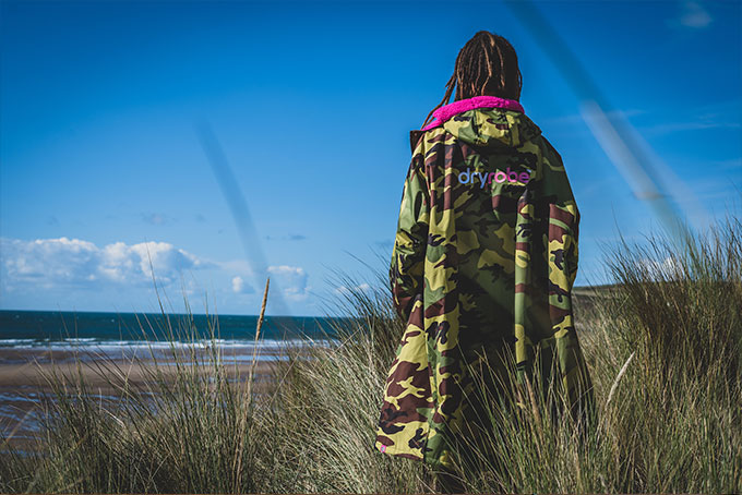 Man stood on shore in camo dryrobe changing robe