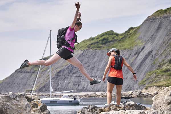 A person jumping btween rocks next to the sea